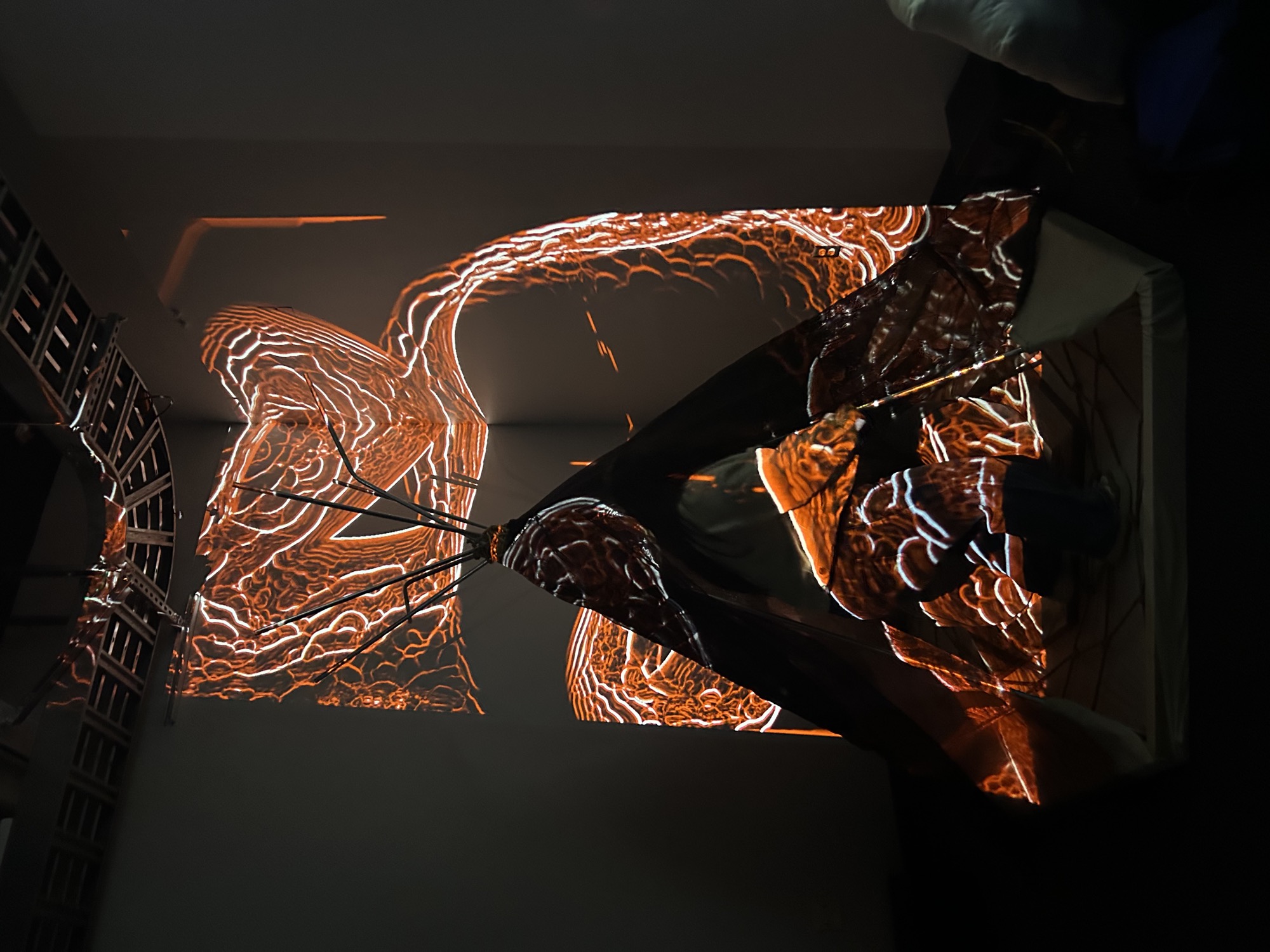 The same tent structure under orange hypnagogic ripples of projected light.